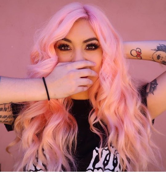 Long and wavy pastel pink hair with side parting is a lot of fun and it looks bold and candy inspired