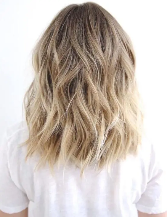 lovely medium-length blonde hair with a shadow root and waves, with volume, is a lovely idea to rock, it's low-maintenance