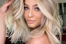 medium-length blonde hair with a shadow root and brighter balayage plus waves and volume is chic