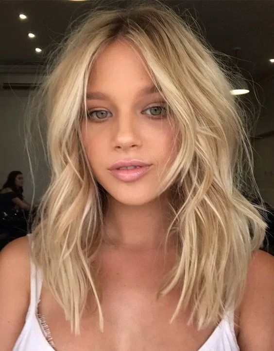 Medium length blonde hair with waves and a shadow root, with a messy touch is a lovely idea to rock