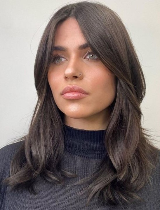 Medium length dark brown hair with chin bangs and waves, middle part looks very stylish and beautiful
