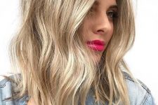 medium-length golden blonde hair with waves, a shadow root and a touch of mess is a stylish and chic solution