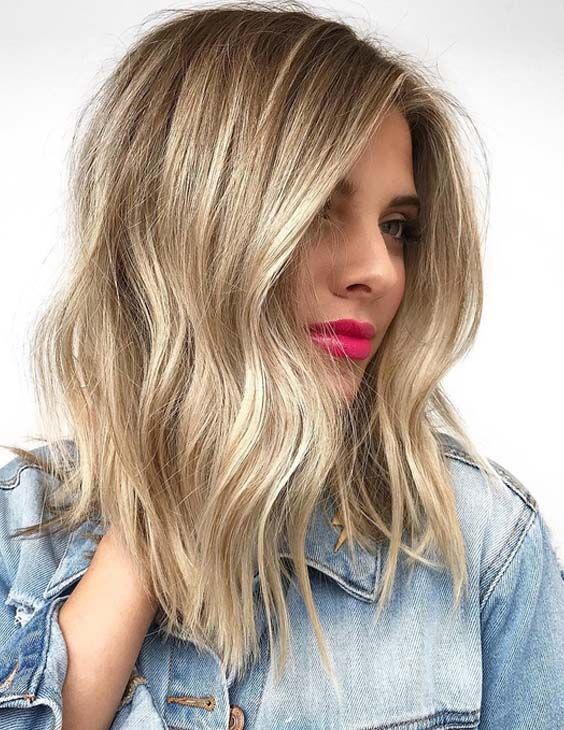 Medium length golden blonde hair with waves, a shadow root and a touch of mess is a stylish and chic solution