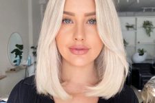 medium-length platinum blonde hair with a darker root, face-framing layers and a lot of volume is a stylishidea