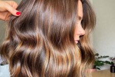 medium-length warm brown hair with gold blonde highlights and slight waves is a stylish and cool idea