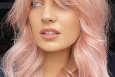 peachy pink shoulder-length hair with a lot of volume and waves and bottleneck bangs is a cool solution with a soft touch of color