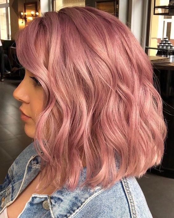 Shoulder length peachy pink hair with a lot of volume and waves looks very chic, eye catching and elegant