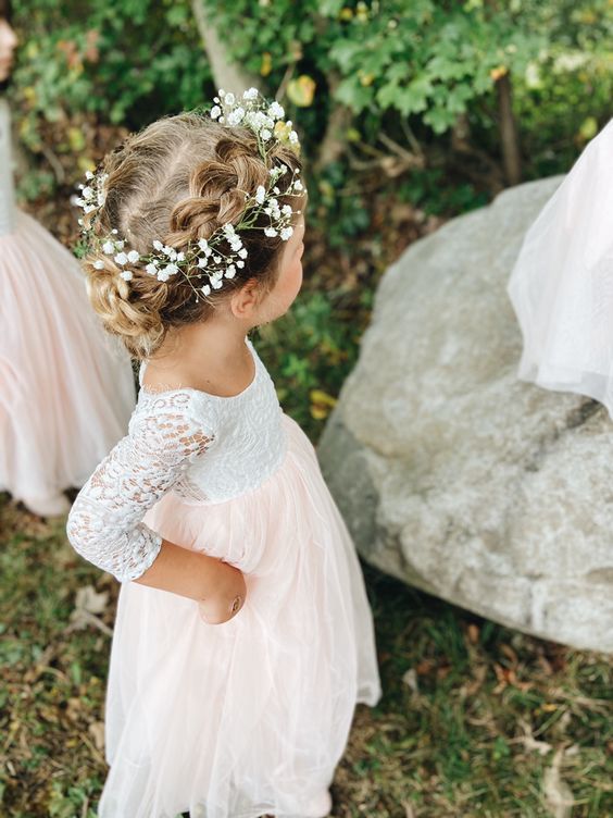 two side braids in a bun and a flower crown result in a super cute and girlish look, perfect for a flower girl at the wedding