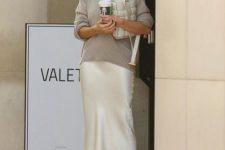 Rosie Huntington Whiteley wearing a grey turtleneck jumper, a white midi slip skirt and white strappy shoes plus a white bag