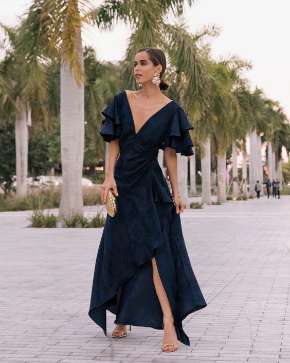 a beautiful and refined winter wedding guest look with a black maxi dress with an asymmetrical skirt, shiny shoes and statement earrings
