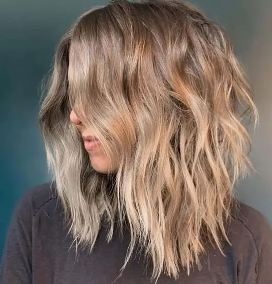 a beautiful beach bronde shaggy haircut with beach waves and central part looks very lovely and relaxed