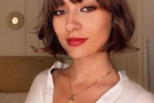 a beautiful brunette chin-length bob with wispy bangs and waves is a stylish and eye-catching idea