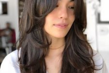 a beautiful dark brunette long butterfly haircut with wavy ends is a stylish idea for long and thick hair