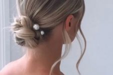 a beautiful woven twisted low bun with pearl hair pins and waves down is a lovely and modern solution for a wedding