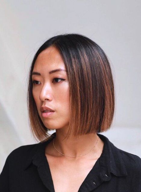 a black chin-length bob with chestnut and copper balayage and a dark root, with straight hair, is a chic idea