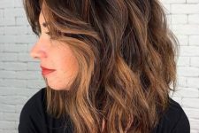 a black medium-length haircut with caramel balayage and waves, with side bangs is a catchy and very chic idea