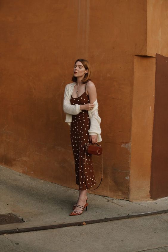 a brown polka dot slip dress, a white cardigan, strappy mules and a small brown bag for a chic look