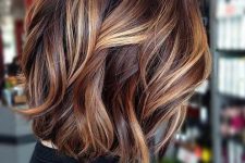 a chic and bold long bob in auburn and brown, with honey blonde balayage and waves is gorgeous
