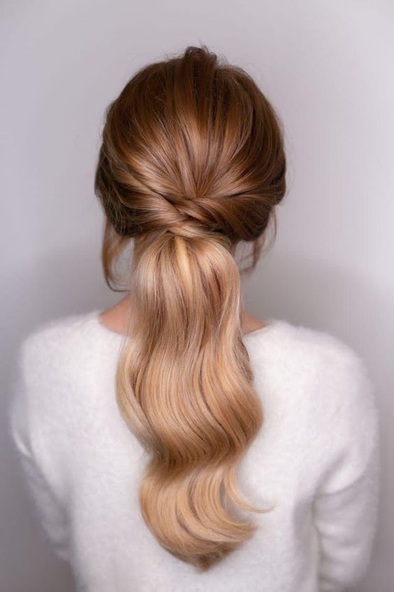 a chic low ponytail with twists and a bump on top plus some waves is a cool and chic idea for many holiday looks