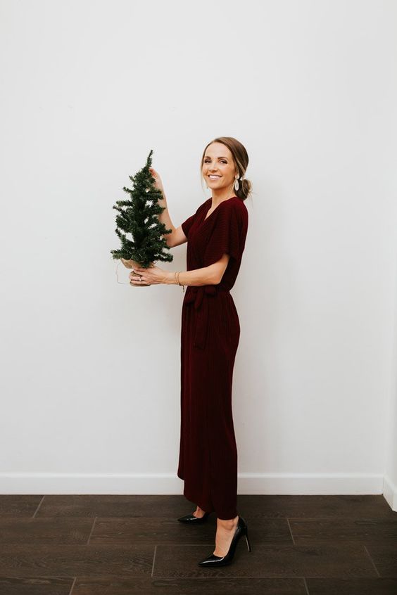 a chic winter wedding guest with a burgundy velvet maxi dress, black heels and statement earrings