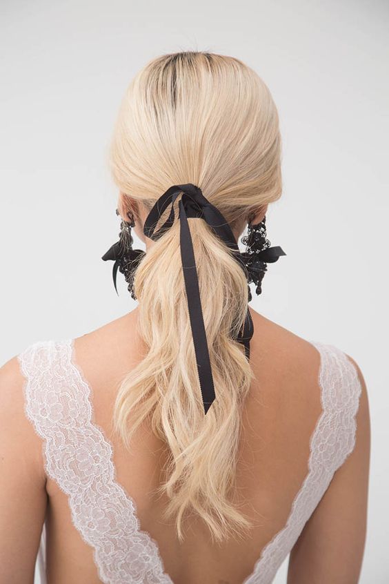 a classy ponytail with a sleek top and waves, with a black bow and statement black earrings with bows