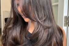 a dark brunette butterfly haircut with a shiny finish and wavy ends is a catchy and stylish idea to try