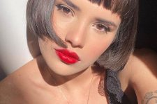 a dark brunette ear-length bob with baby bangs and curled ends plus a shiny finish is a bold Parisian style idea