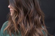 a dark brunette medium length haircut with an ombre effect, waves and volume is a very eye-catching idea