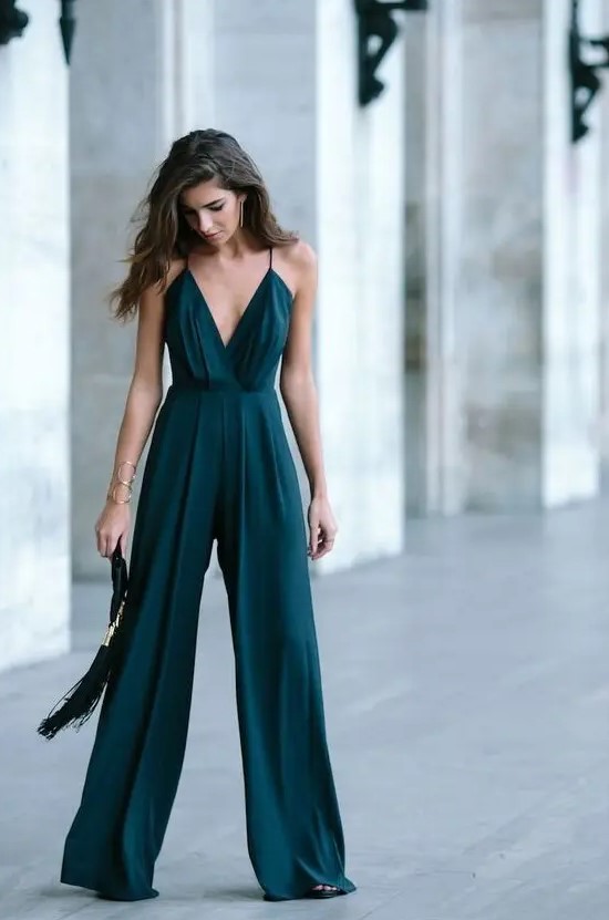 a dark green jumpsuit on spaghetti straps, with wideleg pants and a tassel clutch