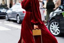 a fantastic red velvet maxi dress with long sleeves and a slit, strappy embellished shoes and a small gold bag