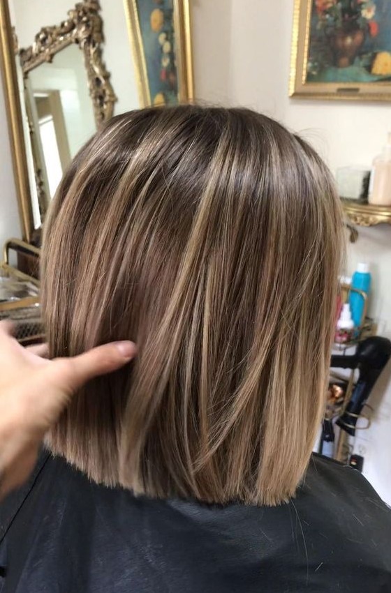 a light brown bob with blonde balayage that gives straight hair a lot of visual volume and interest