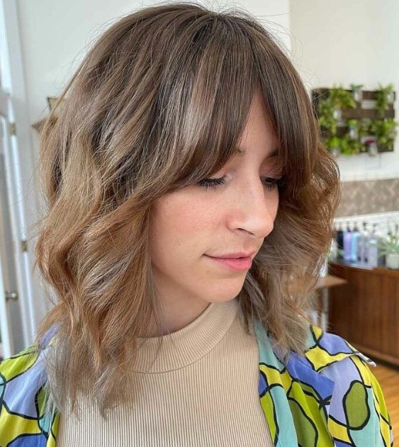 a light brown long wavy bob with curtain fringe and highlights is a cool hairstyle with minimum effort