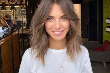 a light brunette shoulder-length hairstyle with curtain bangs and messy texture looks shaggy and cool