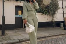 a light green jumpsuit, white strappy shoes, a bead bag for an effortless spring wedding guest look