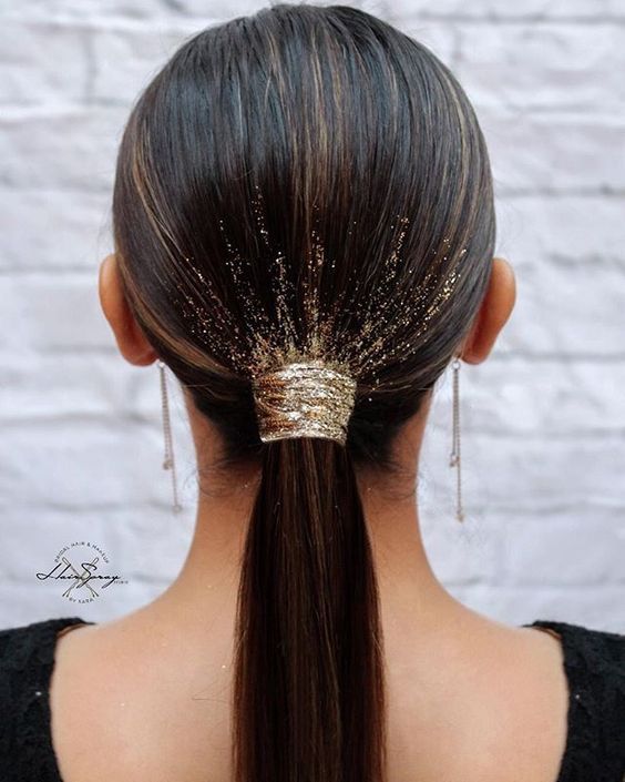 a long ponytail with a gold glitter scrunchie and some additional glitter on the hair is a cool holiday party solution