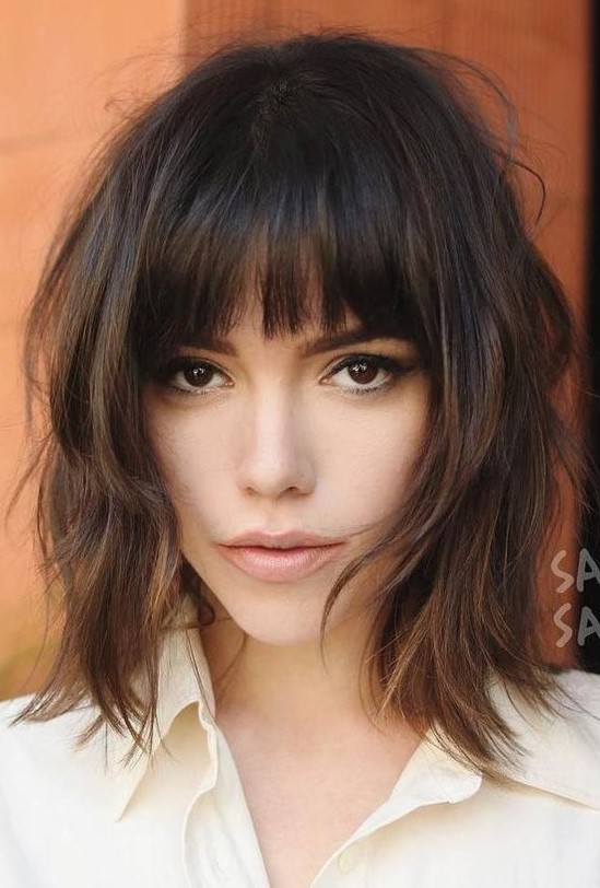 a lovely dark brown long shaggy bob with caramel highlights and a classic fringe plus messy waves is a cool and chic idea
