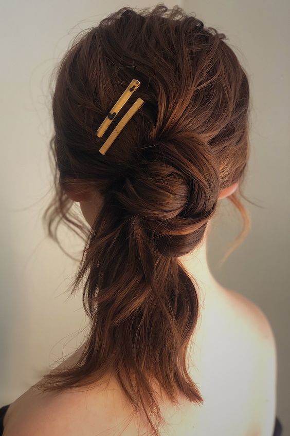 a lovely messy twisted low ponytail with a knot, a messy top and a couple of hair pins