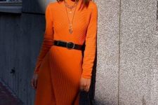 a lovely textural orange sweater dress with a black belt, layered necklaces and a white bag with a monogram