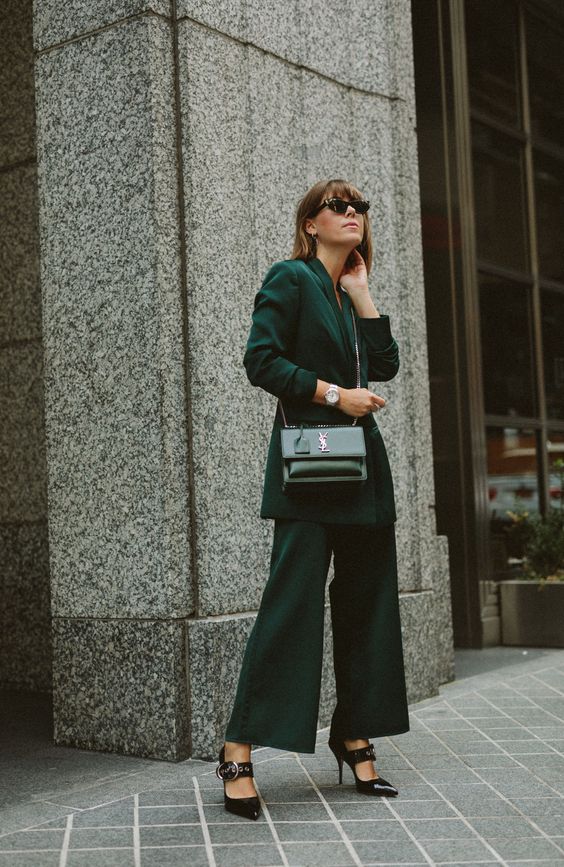 a lovely winter wedding guest outfit with a dark green pantsuit, an oversized blazer, wideleg pants, black shoes and a black bag