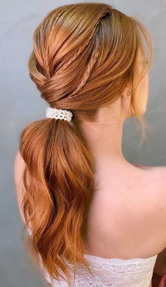 a low twisted ponytail with a bump and small braids on top is a catchy and cool solution