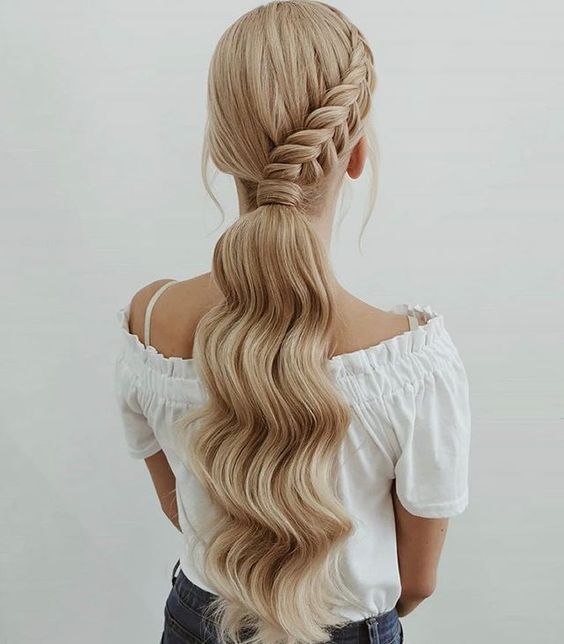 a low wavy ponytail with a side braid and a bump on top is a catchy idea for a party look during the holidays