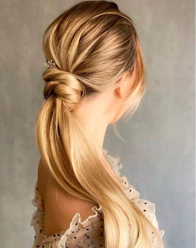 a low wrapped ponytail with a soft framing touch of the edgy bangs that makes the common hairstyle a nice complement to an evening look