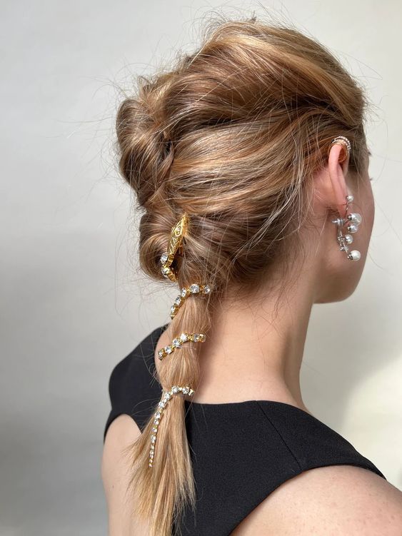 a messy and wavy twisted ponytail with an embellished snake hair piece looks very unusual
