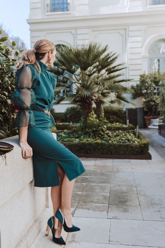 a midi green dress with illusion sleeves and a turtleneck, a side slit, green and gold shoes and gold accessories