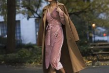 a pink wrap velvet dress with long sleeves and a V-neckline, black heels and a mustard trench