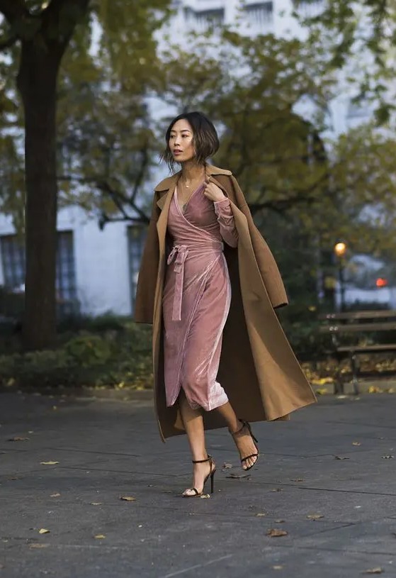 A pink wrap velvet dress with long sleeves and a V neckline, black heels and a mustard trench