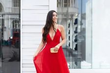 a red maxi dress with spaghetti straps, a deep neckline, a pleated skirt and nude shoes plus a neutral clutch
