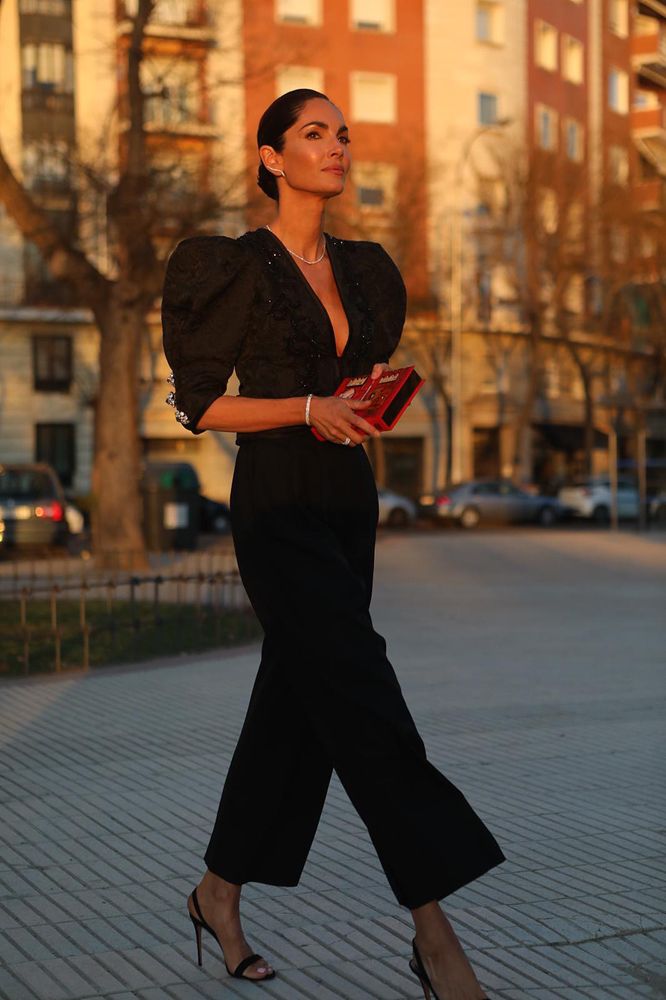 a refined black jumpsuit with puff sleeves, a deep neckline, cropped pants, black slingbacks and chic accessories