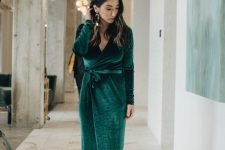 a refined winter wedding guest look with a green velvet wrap maxi dress, black shoes and statement earrings