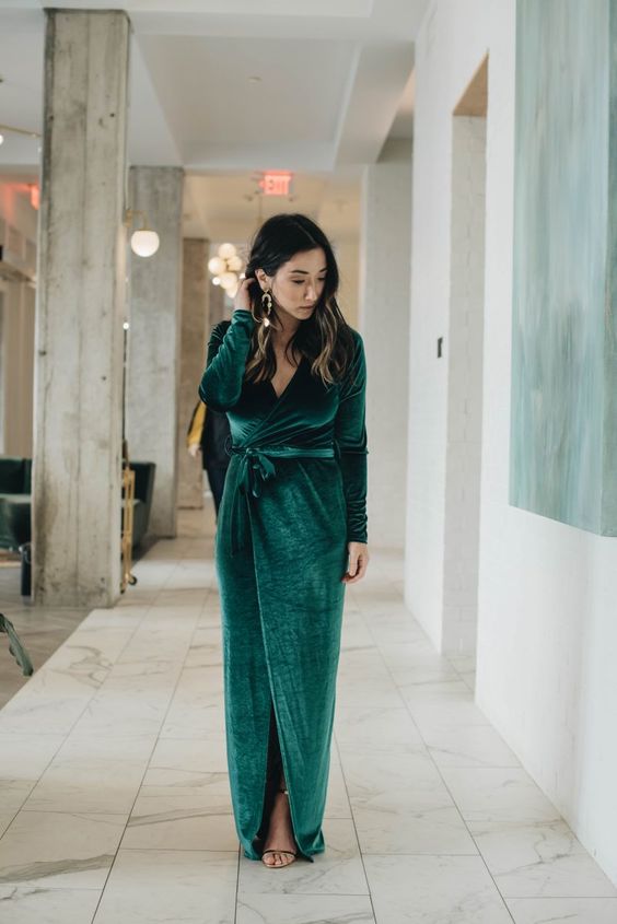 a refined winter wedding guest look with a green velvet wrap maxi dress, black shoes and statement earrings